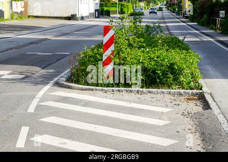 Grün am Straßenrand für erzwungene Geschwindigkeitsreduzierung in der Stadt mit vertikalem rot-weiß gestreiftem Warnschild, Regengärten, Dänemark, Europa Stockfoto