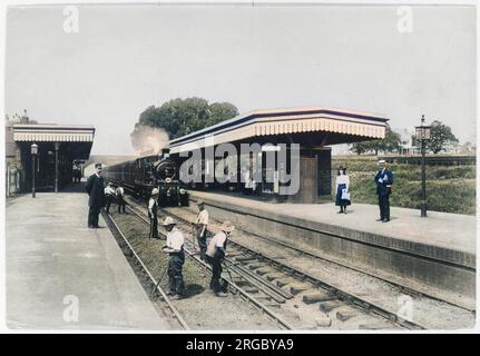 Die Marine arbeitet an der Linie an der Upminster Station im Londoner Bezirk Havering, Greater London, nicht weit von der Grenze zu Essex. Zwei Passagiere warten am hinteren Bahnsteig auf ihren Zug. Stockfoto