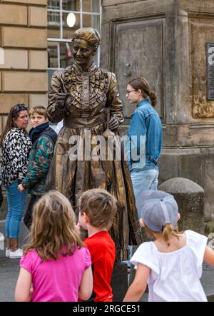 Royal Mile, Edinburgh, Schottland, Großbritannien, 8. August 2023. Edinburgh Fringe Street Performers: Eine lebende Statue der Wissenschaftlerin Marie Curie unterhält die vorbeiziehende Menge mit Kindern. Kredit: Sally Anderson/Alamy Live News Stockfoto