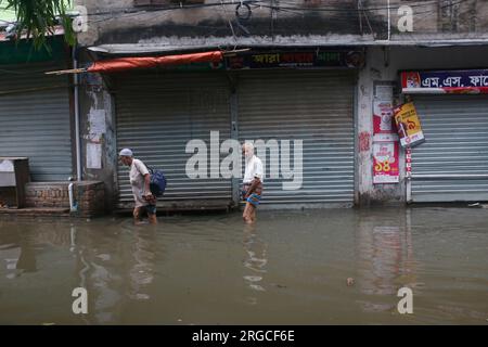 DHAKA, BANGLADESCH - 7. AUGUST 2023: Bewohner gehen nach heftigen Regenfällen in Dhaka, Bangladesch am 7. August 2023 durch die überflutete Straße. Stockfoto