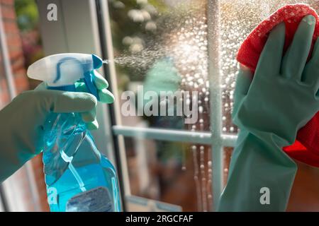 Reinigungsspray durch Ausgießen von Flüssigkeit auf das Glas, um es mit einem Tuch zu reinigen. Stockfoto