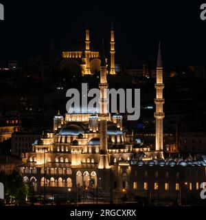 Istanbul, Türkei, Türkiye. Neue Moschee (Yeni Camii) bei Nacht. Blaue Moschee auf einem Hügel im Hintergrund. Stockfoto