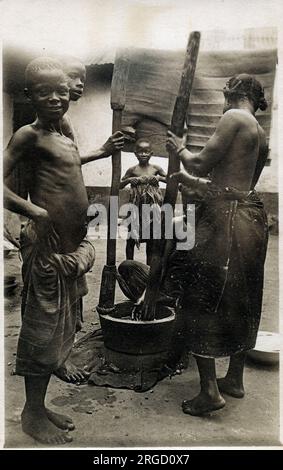 Ghana, Westafrika - Zubereitung von Lebensmitteln mit einem großen Mörser und Stößel zum Zerstoßen von Getreide und Lebensmitteln. Stockfoto