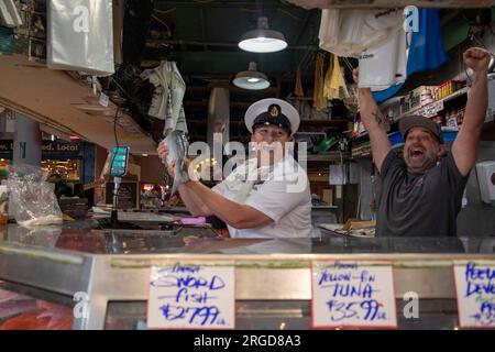 Seattle, Washington, USA. 2. Aug. 2023. Chief Mass Communication Specialist Gretchen Albrecht aus Chino Hills, Kalifornien, fängt während der Seattle Fleet Week vom 2. August 2023 auf dem Pike Place Market mit Matrosen Fische. Die Seattle Fleet Week ist eine feierliche Feier der Seeverkehrsdienste und bietet den Einwohnern Washingtons die Gelegenheit, Matrosen, Marines und Küstenwachmänner zu treffen und aus erster Hand die neuesten Fähigkeiten der Seeverkehrsdienste der todayâs USA und Kanadas zu erleben. (Foto: Madison Cassidy) Guthaben: U.S. Navy/ZUMA Press Wire/ZUMAPRESS.com/Alamy Live News Stockfoto