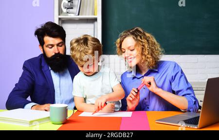 Lehrer helfen Kindern aus der Grundschule bei Hausaufgaben. Wissen, Studieren und Lernen. Ein kleiner Schüler in der Grundschule Stockfoto