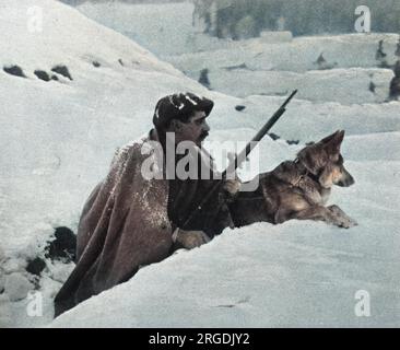 Ein französischer Soldat blickt über einen Schlitzgraben, während sein deutscher Schäferhund ebenfalls wachsam ist. Der Hund ist bereit, beim ersten verdächtigen Anzeichen eines Angriffs zu knurren. Stockfoto