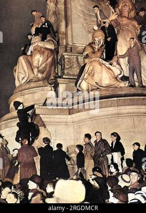 Ein Teil der riesigen Menschenmenge am Trafalgar Square, der an der Schranke steht, nachdem er die ganze Nacht gewartet hat, um die Krönungsprozession von König George VI. Zu sehen Um 2am war der Platz fast voll und lange vor der ersten Prozession mussten die Tore geschlossen werden. Beachten Sie den Polizisten im Hintergrund, der auf einen der Löwen am Trafalgar Square klettert, vermutlich um Kletterer wegzuscheuchen! Stockfoto