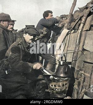 Irgendwo in Frankreich kocht ein britischer Soldat sein Abendessen auf einem Brazier in den Gräben, während seine Kameraden Ausschau halten. Stockfoto