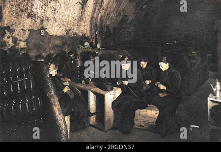 Französische Frauen stricken in einem düsteren Weinkeller, der in Reims, einem Zufluchtsort vor Patronenfeuer in der häufig bombardierten Stadt, von Kerzen dunkel beleuchtet wird, "Trost" für Soldaten. Stockfoto