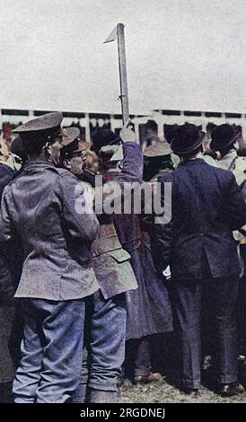 Soldaten, die von der Front aus auf Urlaub sind, beobachten den Grand National in Aintree auf neuartige Weise, indem sie ein Grabenperiskop verwenden, um über die Rennbahn zu blicken. Stockfoto