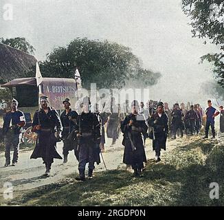 Belgische Soldaten auf dem marsch im Dorf St. Trond, in den ersten Wochen des Ersten Krieges, auf dem Weg zur Front. Ganz rechts auf dem Bild ist ein Priester, der ein Rotes Kreuz-Abzeichen auf seinem Arm trägt. Auf der linken Seite befindet sich ein Wagen, der einem örtlichen Händler gehört. Stockfoto