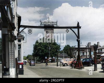 Ein Blick auf die High Street, Crawley, Sussex, England, mit dem charakteristischen Zeichen des „George Hotel“, das auf Holzbalken gehalten ist, erstreckt sich über die Straße. Stockfoto