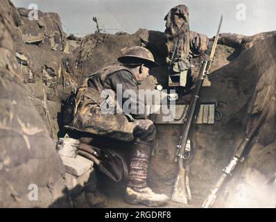 Ein Soldat in einem Wachposten in einem Graben, der ein getarntes Periskop benutzt, um die britische Front in Frankreich während des Ersten Weltkriegs 1917 zu beobachten. Er hat ein kleines Magazin Lee Enfield Mk III Gewehr neben sich. Stockfoto