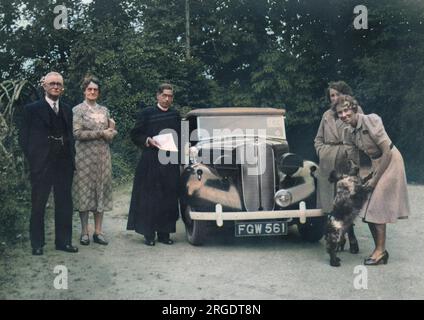 Eine Gruppe von fünf Personen mit einem Spaniel und einem Auto. Stockfoto