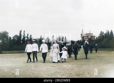 Zar Nicholas II. Von Russland spaziert durch die Landschaft von Krasnoe Selo in einem großen Gefolge, zu dem seine Frau Alexandra Feodorowna, eine seiner Töchter, andere Familienmitglieder und mehrere Beamte gehören. Stockfoto