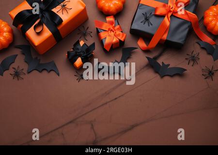 Komposition mit Geschenkschachteln, Spinnen und Fledermäusen für Halloween auf braunem Hintergrund Stockfoto