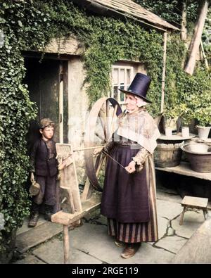 Walisische Frau vor einer Hütte mit einem drehenden Rad, Wales. Stockfoto