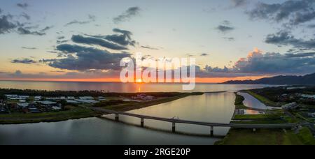 Sonnenuntergang am Horizont über dem Meer von Japan am Küstenfluss und an der Brücke Stockfoto