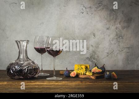 Rotwein in zwei Stängelgläsern und Kristallkaraffe mit Blaukäse und Feigen Stockfoto