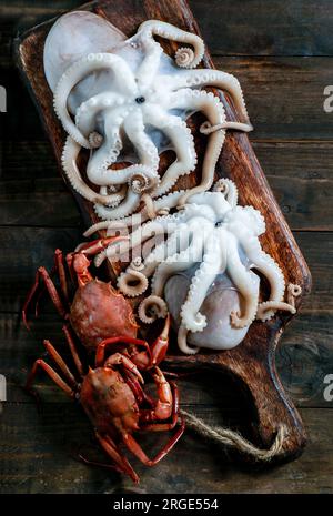 Meeresfrüchtetafel mit Krabben, Sardinen und Muscheln, Fisch und Tintenfisch auf dunklem Holzhintergrund. Draufsicht, Nahaufnahme Stockfoto