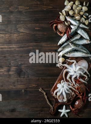 Meeresfrüchtetafel mit Krabben, Sardinen und Muscheln, Fisch und Tintenfisch auf dunklem Holzhintergrund. Draufsicht, Nahaufnahme Stockfoto