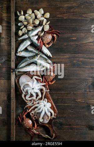 Meeresfrüchtetafel mit Krabben, Sardinen und Muscheln, Fisch und Tintenfisch auf dunklem Holzhintergrund. Draufsicht, Nahaufnahme Stockfoto