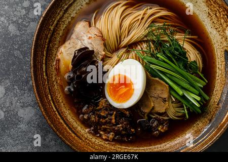 Ramen-asiatische Nudeln in Brühe mit Rinderzungenfleisch, Pilz und Ei in der Schüssel Stockfoto
