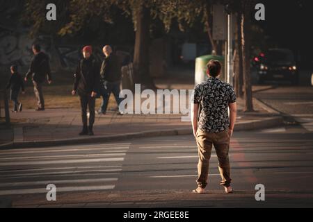 Bild eines Mannes, der auf grünes Licht wartet, um im Herbst bei Sonnenuntergang eine Kreuzung im Stadtzentrum von Belgrad zu überqueren. Stockfoto