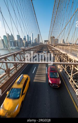 Ein gelbes Taxi und ein rotes Auto, das über die Brooklyn Bridge fährt, von oben gesehen Stockfoto