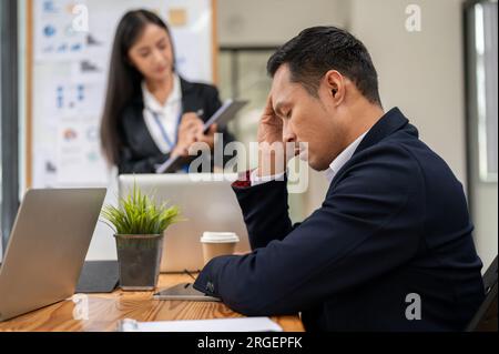 Ein gestresster asiatischer Geschäftsmann ist in der Besprechung, besorgt und verärgert über seine Projektergebnisse und besorgt über sein Scheitern. Rückansicht Stockfoto