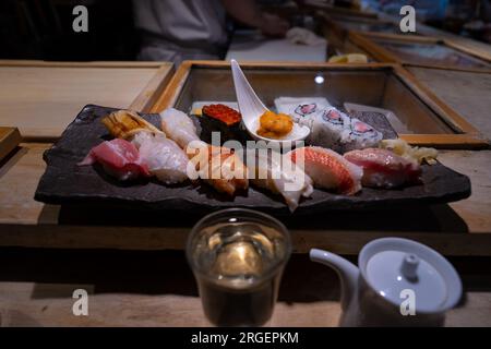 Sushi-Platte, eine Auswahl an rohem Fisch und Reissnacks mit Stäbchen. Stockfoto