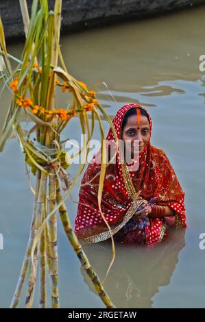 Indianerin steht im heiligen Ganges und betet während des Chhath - Hindu Festivals in Varanasi für die untergehende und aufgehende Sonne Stockfoto