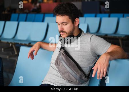 Mann versuchte am Flughafen zu schlafen, traurig, weil sein Flug verspätet war. Stockfoto