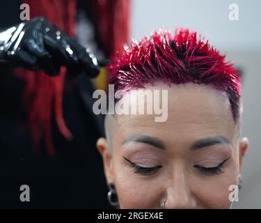 Der Friseur färbt das Haar einer Asiatin in Rosa. Kurzer, extremer Haarschnitt. Stockfoto