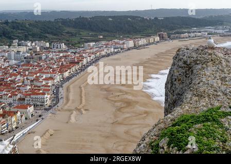 Stadt Nazare, Portugal - Blick unter die Klippen. Blick von oben auf die Stadt Nazare und den Sandstrand. Die größten Wellen der Welt sind in Nazare, Leiria Distric Stockfoto