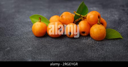 Obstloquat Medlar isoliert auf dunklem Tischhintergrund. Auch Nispero und Eriobotrya japonica genannt. Schließen. Stockfoto