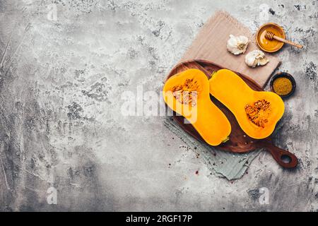 Hälften rohen organischen Butternusskürbis mit Gewürzen und Zutaten zum Kochen Stockfoto