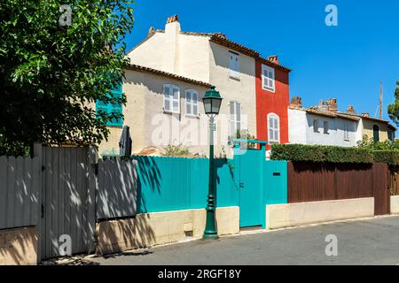 Farbenfrohe Häuser hinter einem Holzzaun unter blauem Himmel in Port Grimaud - Stadt an der französischen Riviera. Stockfoto