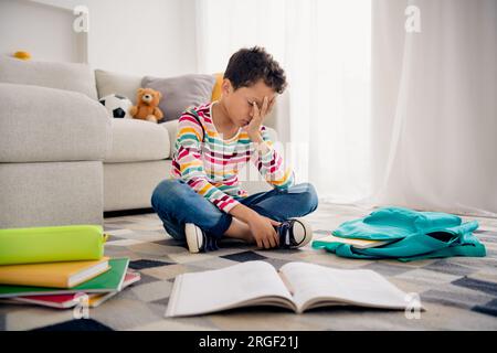 Ganzkörperfoto des kleinen Sohnes Schuljunge Hand Kopf gelangweilt schlafend nicht mögen Literatur lesen isolierter Wohncouch Hintergrund Stockfoto