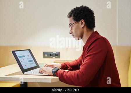 Minimales Seitenbild eines jungen arabischen Geschäftsmannes mit Brille und Computer am Arbeitsplatz, Kopierbereich Stockfoto