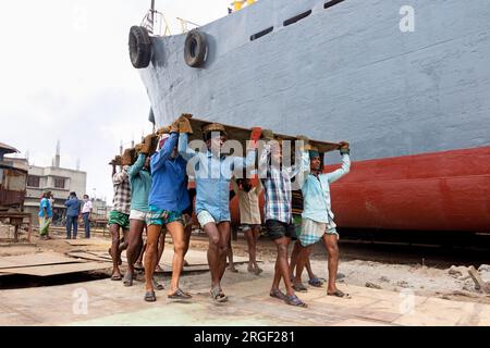 Dhaka, Dhaka, Bangladesch. 9. Aug. 2023. Eine Gruppe von Gepäckträgern trägt eine schwere Stahlplatte von 250 kg auf einer Werft am Ufer des Buriganga in Keraniganj, nahe Dhaka, Bangladesch. Dutzende von Werften, die 30,96 Hektar an der Küste von Buriganga belegen, sind seit 50 Jahren in Betrieb. Es wird hauptsächlich zur Reparatur und Reparatur alter Schiffe und zum Bau neuer Schiffe verwendet. Die Arbeit auf dem Werftplatz funktioniert ohne Helme, Gesichtsmasken oder Sicherheitsschuhe. Sie arbeiten den ganzen Tag lang hart, erhalten aber trotzdem Mindestlöhne. Mit einer zunehmenden Anzahl von Bestellungen sowohl von lokalen als auch von globalen Käufern, ist der Schiffbauer Stockfoto