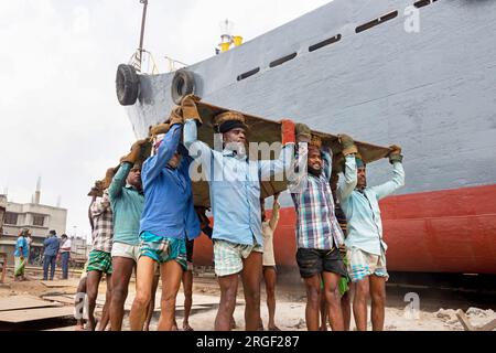 Dhaka, Dhaka, Bangladesch. 9. Aug. 2023. Eine Gruppe von Gepäckträgern trägt eine schwere Stahlplatte von 250 kg auf einer Werft am Ufer des Buriganga in Keraniganj, nahe Dhaka, Bangladesch. Dutzende von Werften, die 30,96 Hektar an der Küste von Buriganga belegen, sind seit 50 Jahren in Betrieb. Es wird hauptsächlich zur Reparatur und Reparatur alter Schiffe und zum Bau neuer Schiffe verwendet. Die Arbeit auf dem Werftplatz funktioniert ohne Helme, Gesichtsmasken oder Sicherheitsschuhe. Sie arbeiten den ganzen Tag lang hart, erhalten aber trotzdem Mindestlöhne. Mit einer zunehmenden Anzahl von Bestellungen sowohl von lokalen als auch von globalen Käufern, ist der Schiffbauer Stockfoto