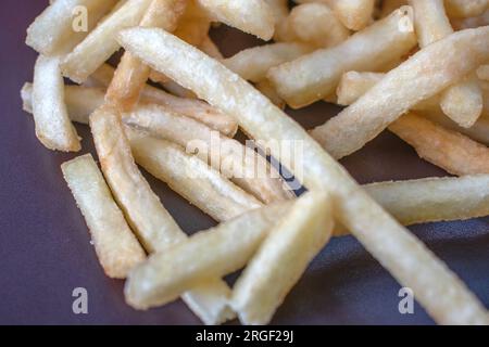 Pommes frites: Nahaufnahme mit frisch zubereiteten und perfekt goldenen Pommes frites vor dunklem Hintergrund. Der Fokus liegt auf einem fachmännischen Ansatz Stockfoto