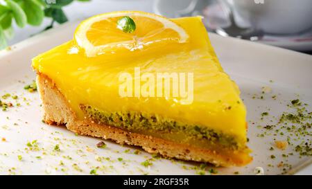 Zitronen-Käsekuchen mit Sauce serviert auf einem weißen Teller Stockfoto