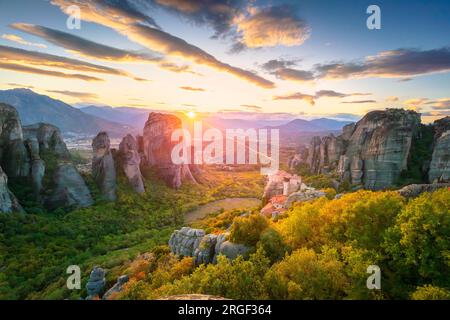 Meteora, Griechenland. Panoramablick auf Meteora, Griechenland bei romantischem Sonnenuntergang mit echter Sonne und Sonnenuntergang am Himmel. Meteora - unglaublicher Sandsteinfelsen für Stockfoto
