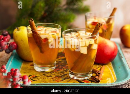 Herbst- und Wintergetränk mit Äpfeln, Birnen und Zimt in Gläsern auf dem altmodischen Tablett Stockfoto