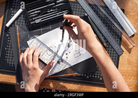 Architekt und Konstrukteur, die präzise an einem Projekt arbeiten, zeichnen Skizzen und technische Entwürfe auf Papier mit professionellen Werkzeugen wie Linealen, Kompass und Stockfoto
