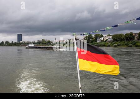 Frachtschiff auf dem Rhein, Rheinufer im Bezirk Mülheim, deutsche Flagge auf einem Ausflugsboot, Köln, Deutschland. Frachtschiff auf dem Rhein, R Stockfoto