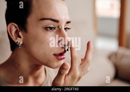 Schwuler Mann mit Piercings, der sich zu Hause versöhnt Stockfoto