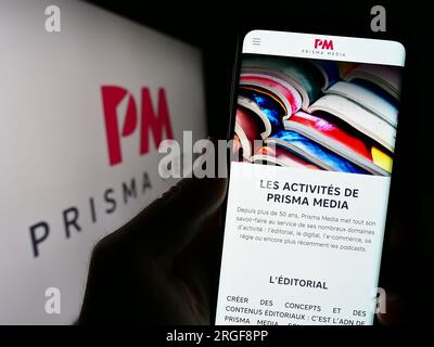 Person, die ein Smartphone mit einer Webseite des französischen Verlagsunternehmens Prisma Media auf dem Bildschirm vor dem Logo hält. Konzentrieren Sie sich auf die Mitte des Telefondisplays. Stockfoto